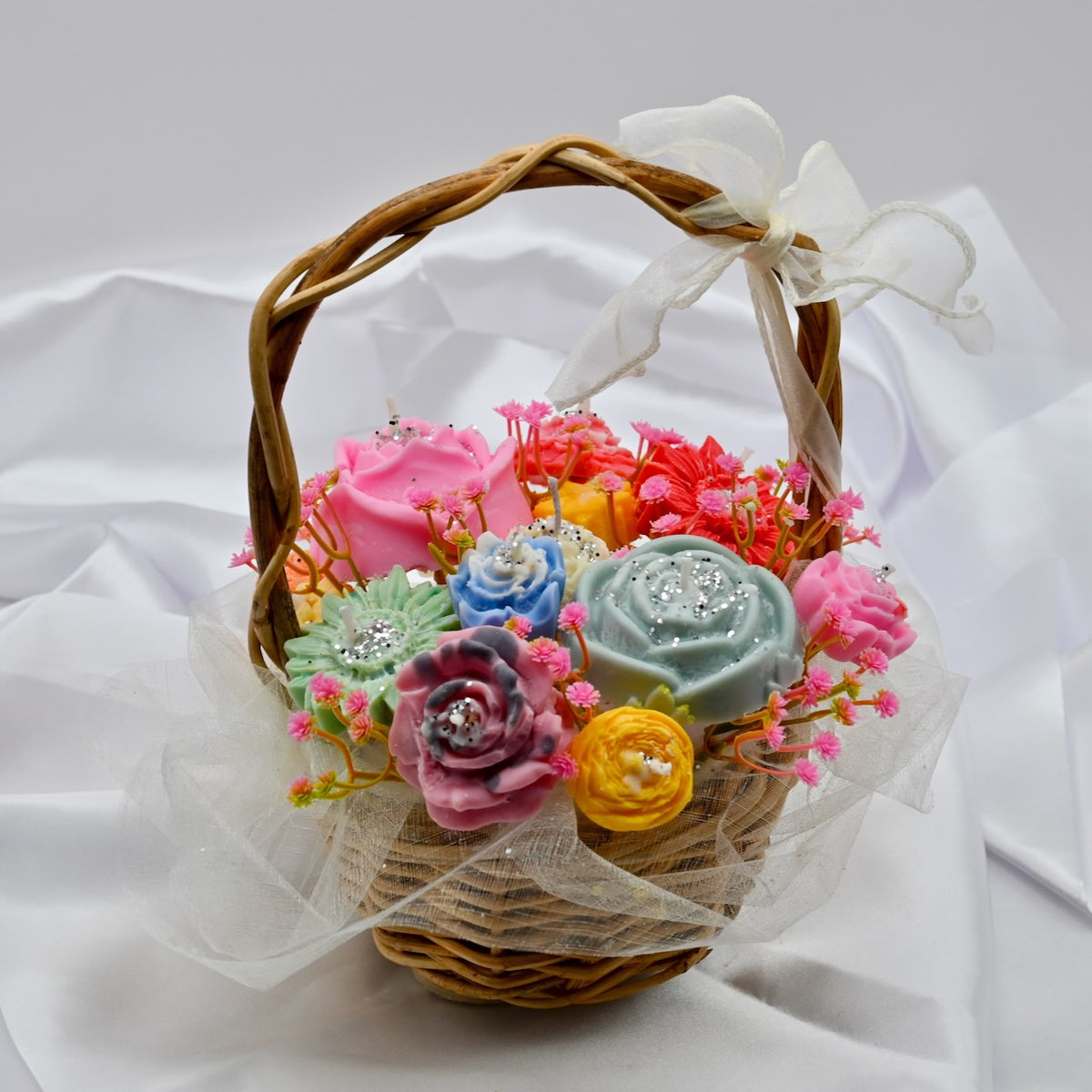 Colorful soy wax flower candle bouquet with pink decorative accents in a ribbon-wrapped wicker basket