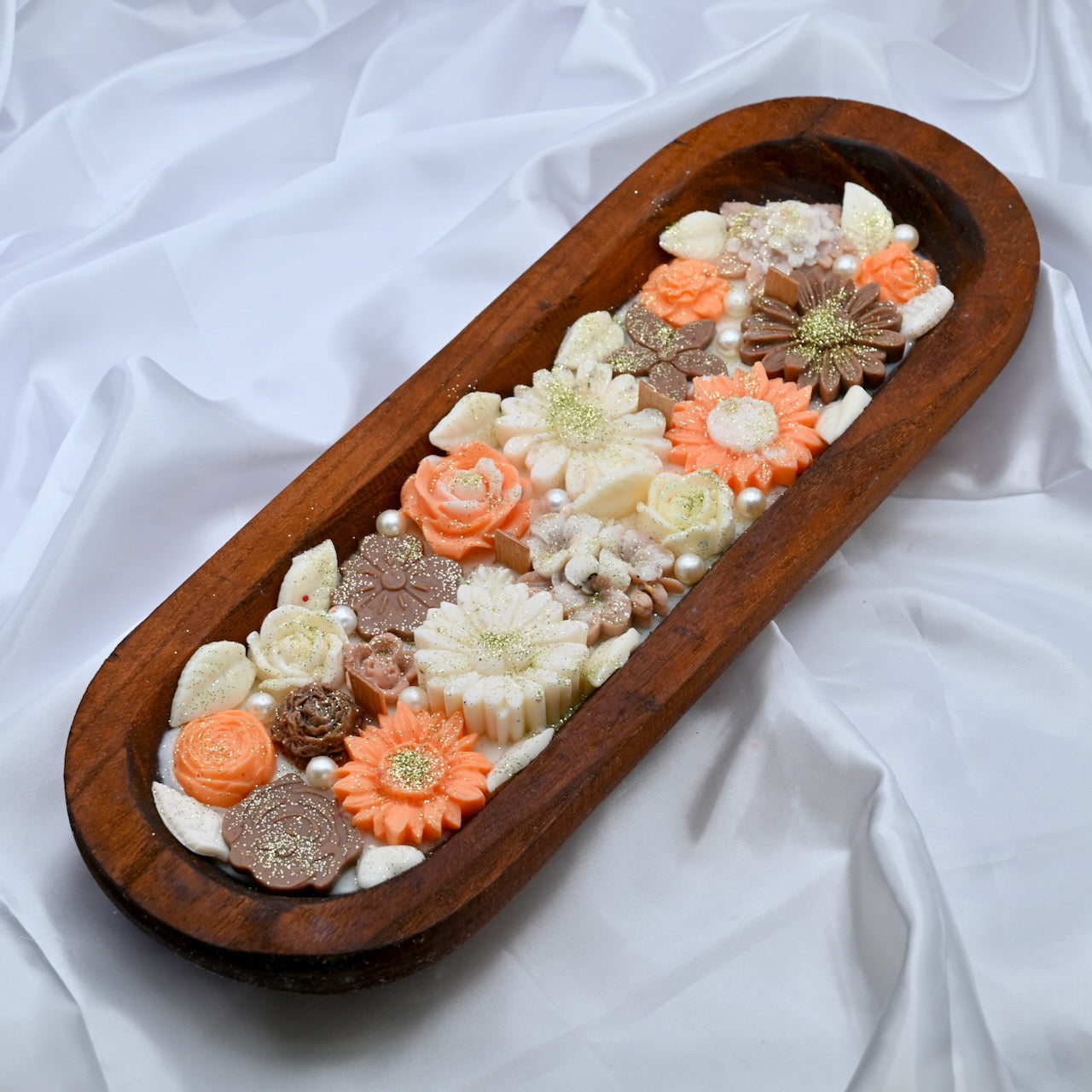 Right top view of wooden tray with multiple floral-shaped colorful pink and brown candles