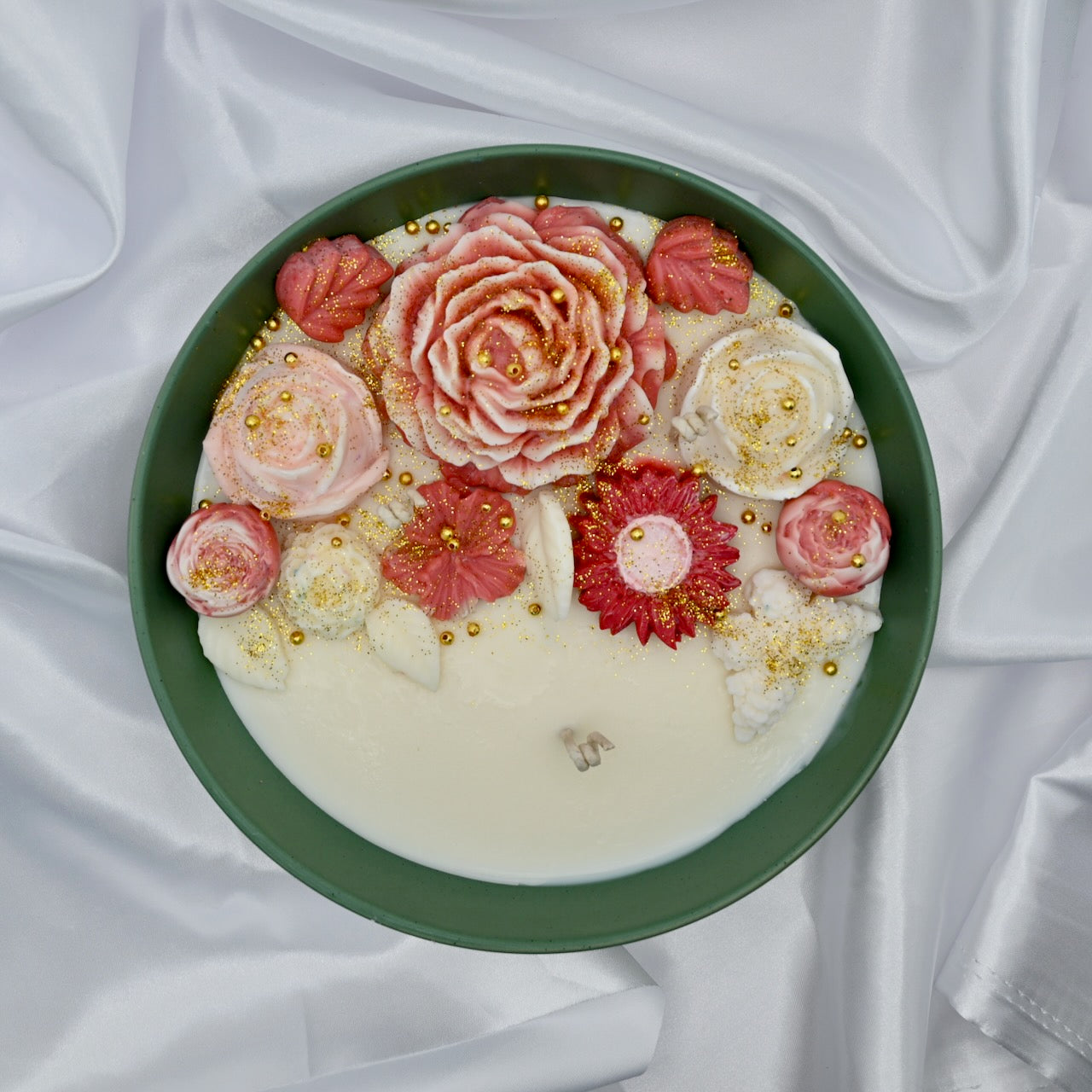 Top view of green bowl candle with pink and blush floral wax design and gold accents
