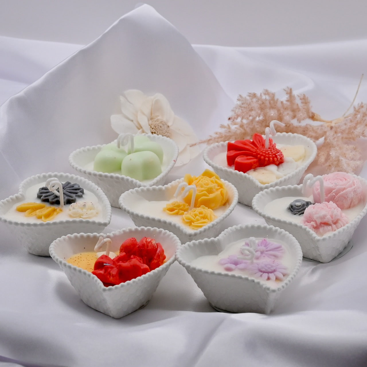 Heart-shaped bowls with colorful candies on a white fabric background