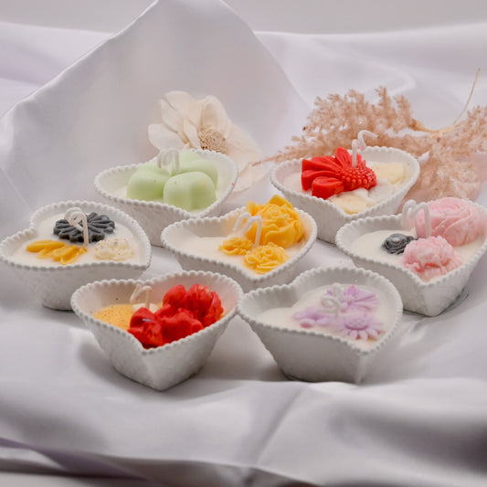 Small white bowls with colorful candles on a white fabric background