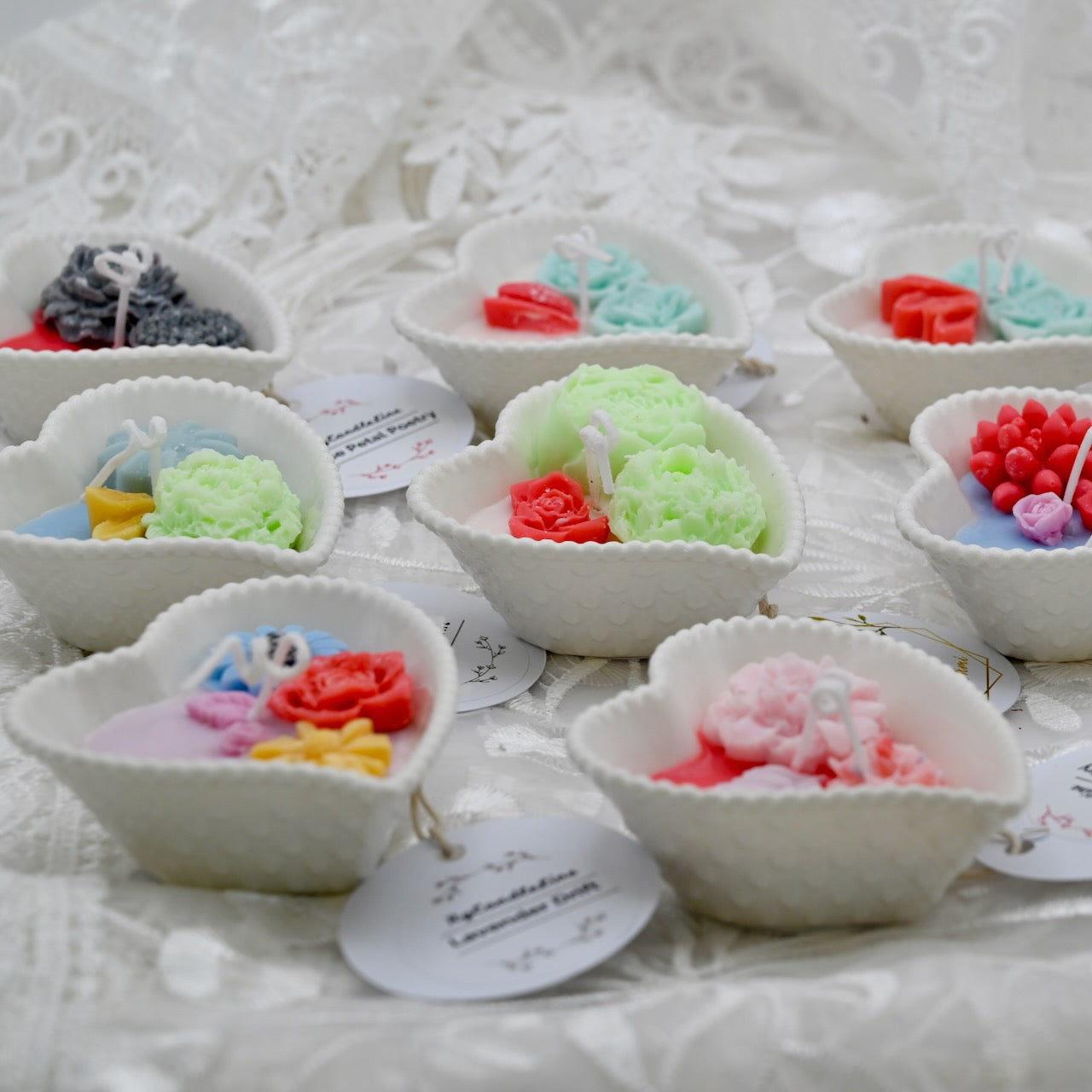 Small white bowls with colorful floral decorative candle designs on a textured white background