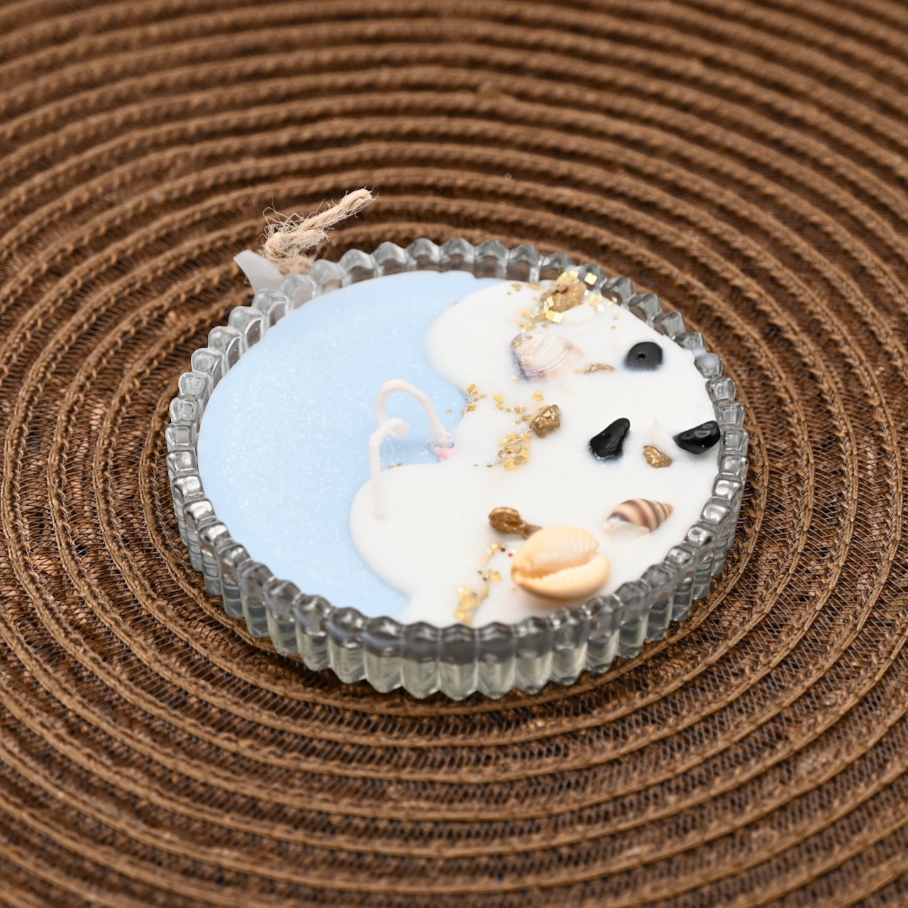 Decorative candle with seashells on a textured brown surface