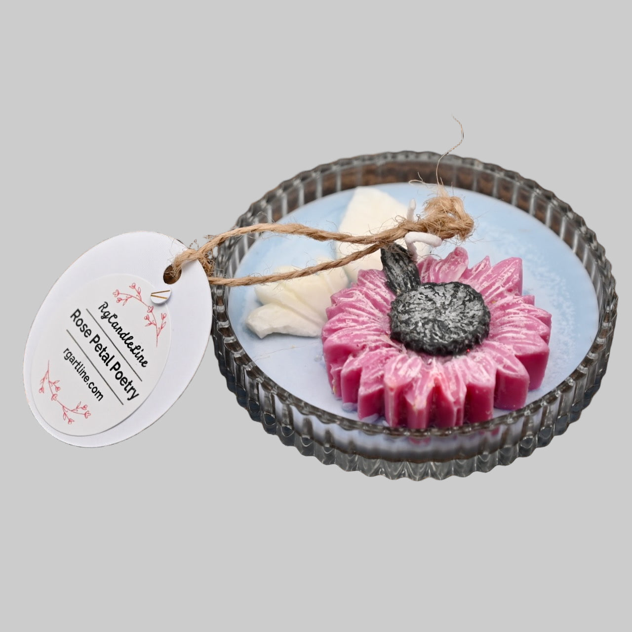 Decorative candle with a pink flower design on a gray background