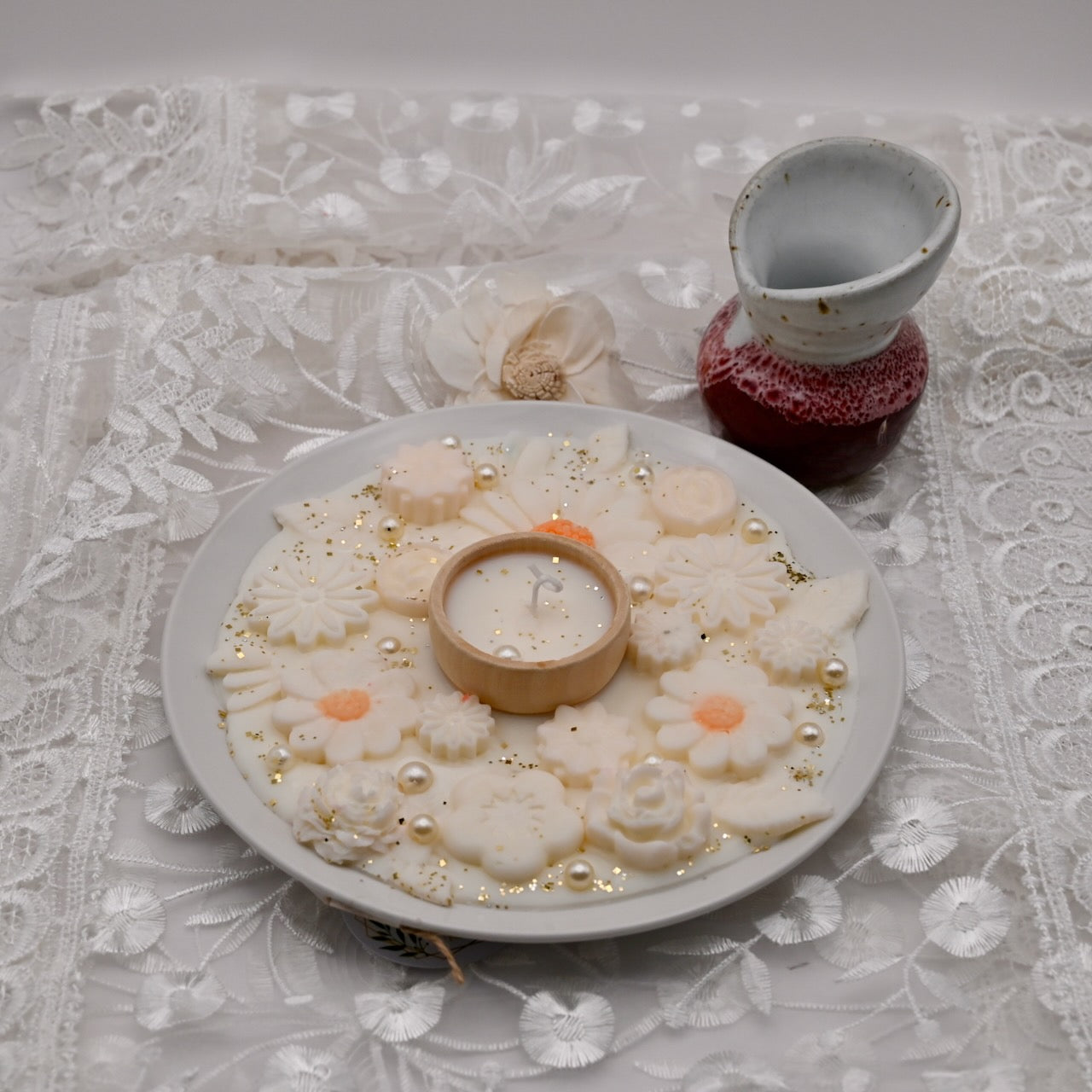 Decorative plate with floral arrangements and a small candle on a lace tablecloth.  Diwali decorative plate.