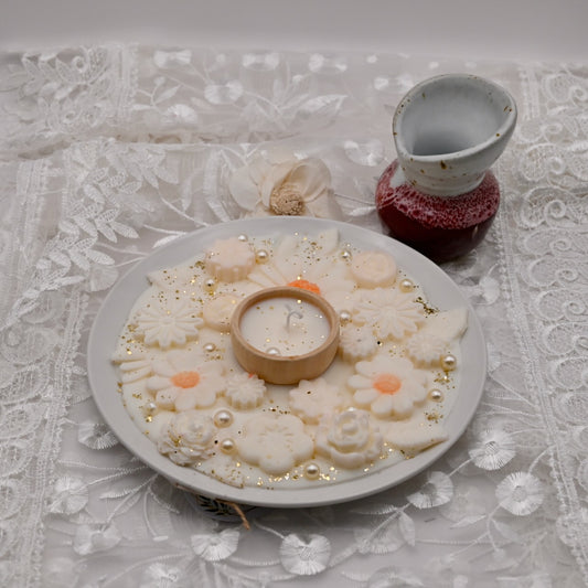Decorative plate with floral arrangements and a small candle on a lace tablecloth.  Diwali decorative plate.