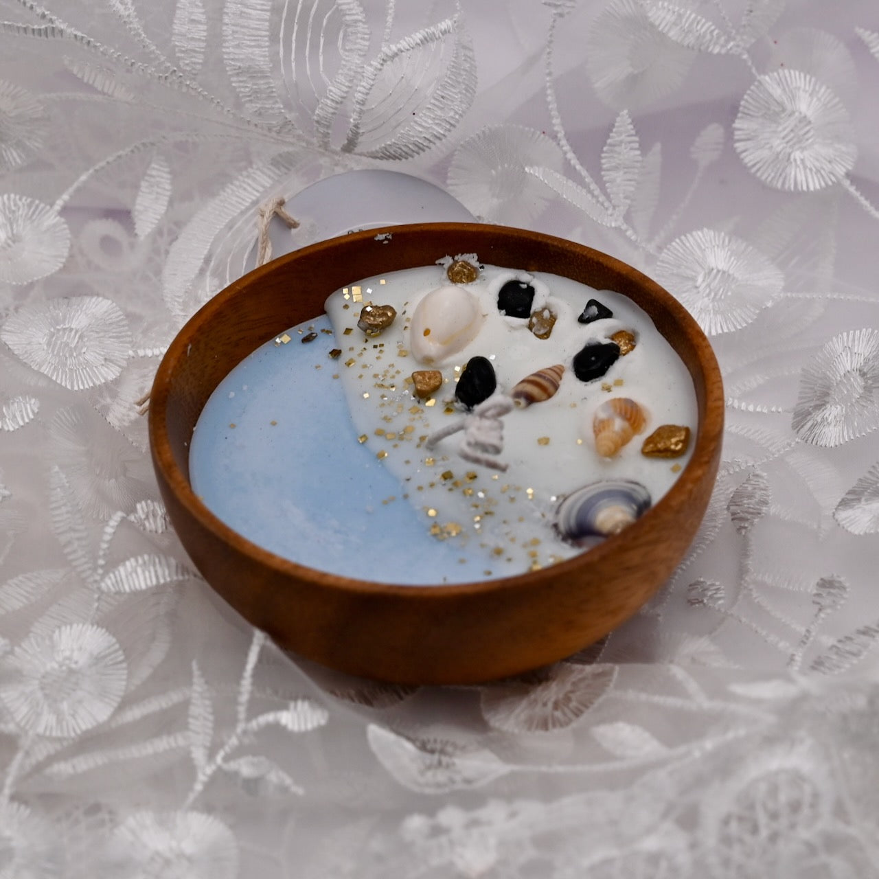 Wooden bowl with a decorative candle on a floral-patterned fabric background