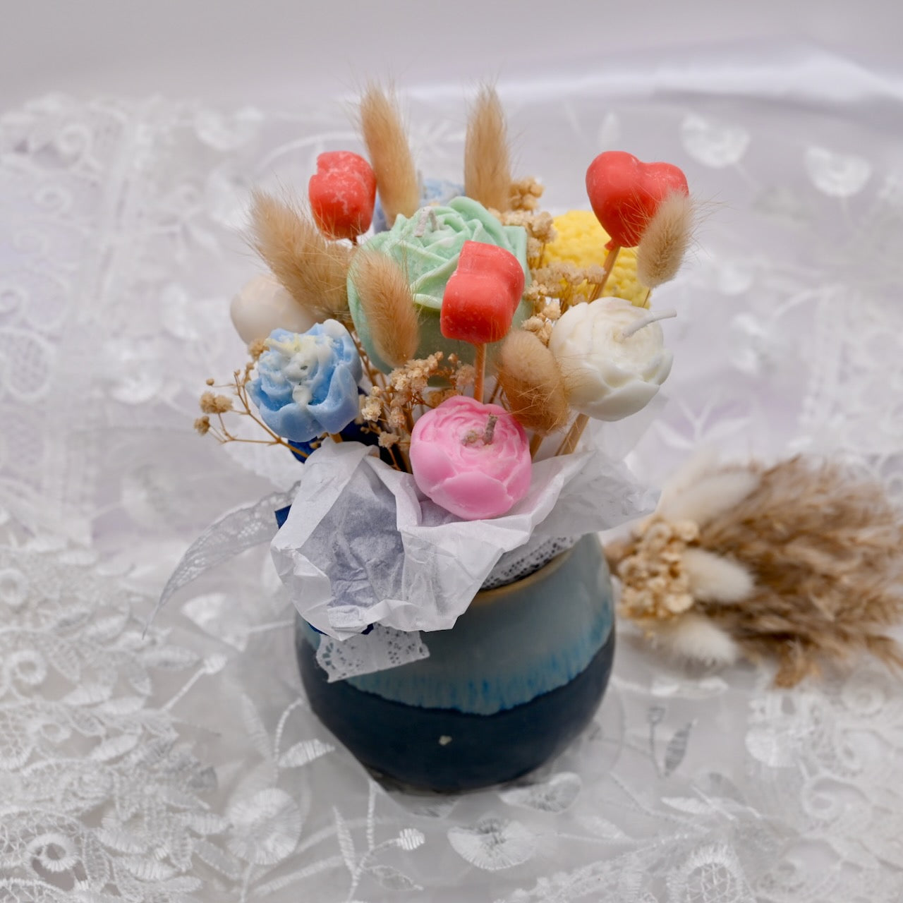 Decorative flower arrangement in a small vase on a textured white background