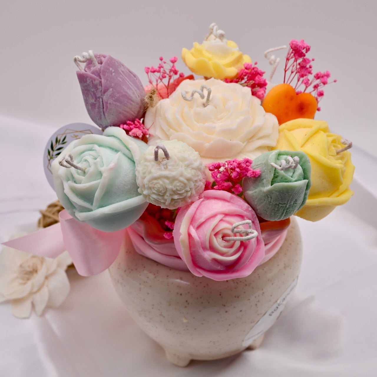 Decorative arrangement of soap flowers in a small pot on a white background
