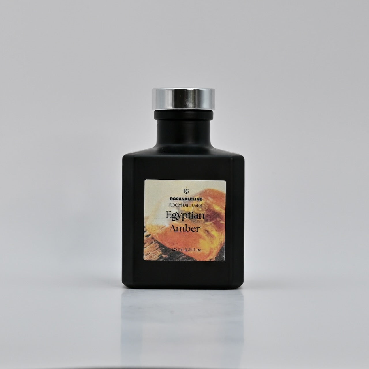 Black bottle of Egyptian Amber cologne with a silver cap on a gray background