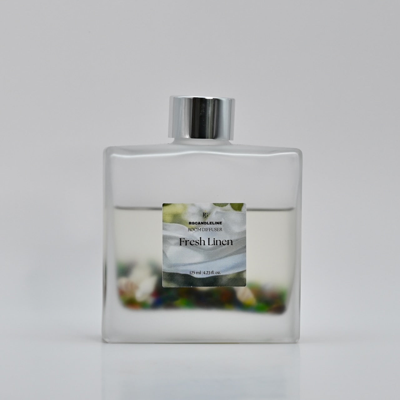 Clear bottle of 'Fresh Linen' room diffuser with a silver cap on a light gray background