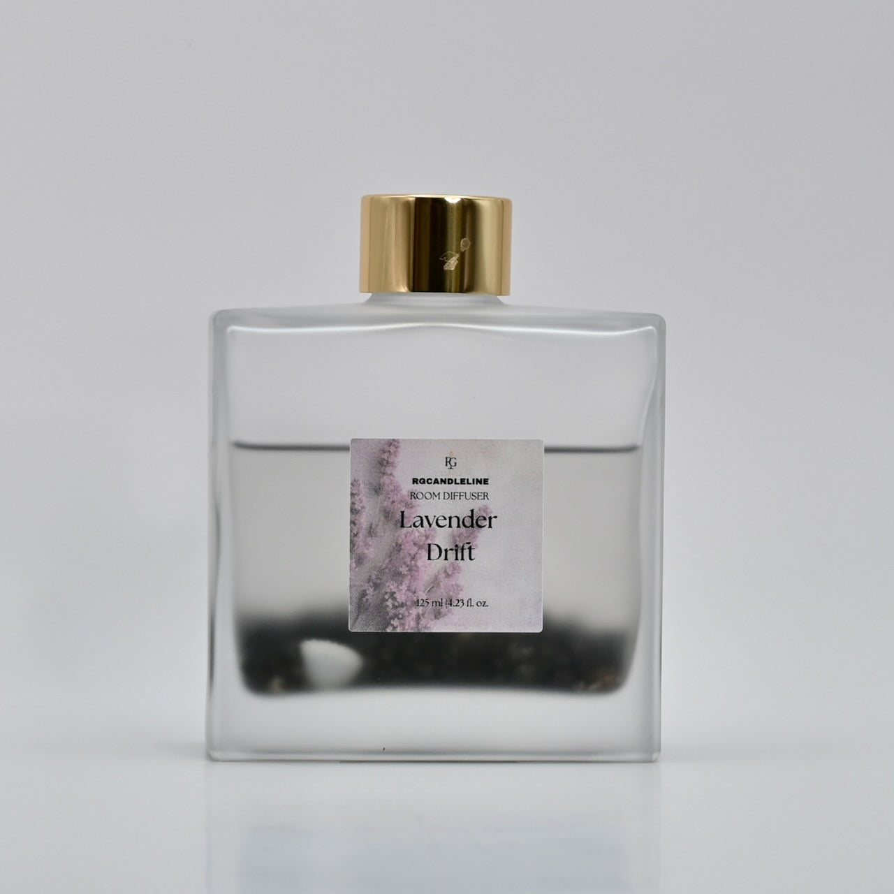 Clear bottle with gold cap and lavender-themed label on a gray background