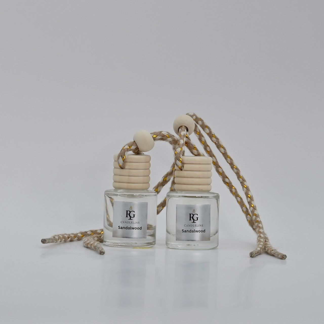 Two sandalwood-scented car air fresheners with a rope on a light gray background