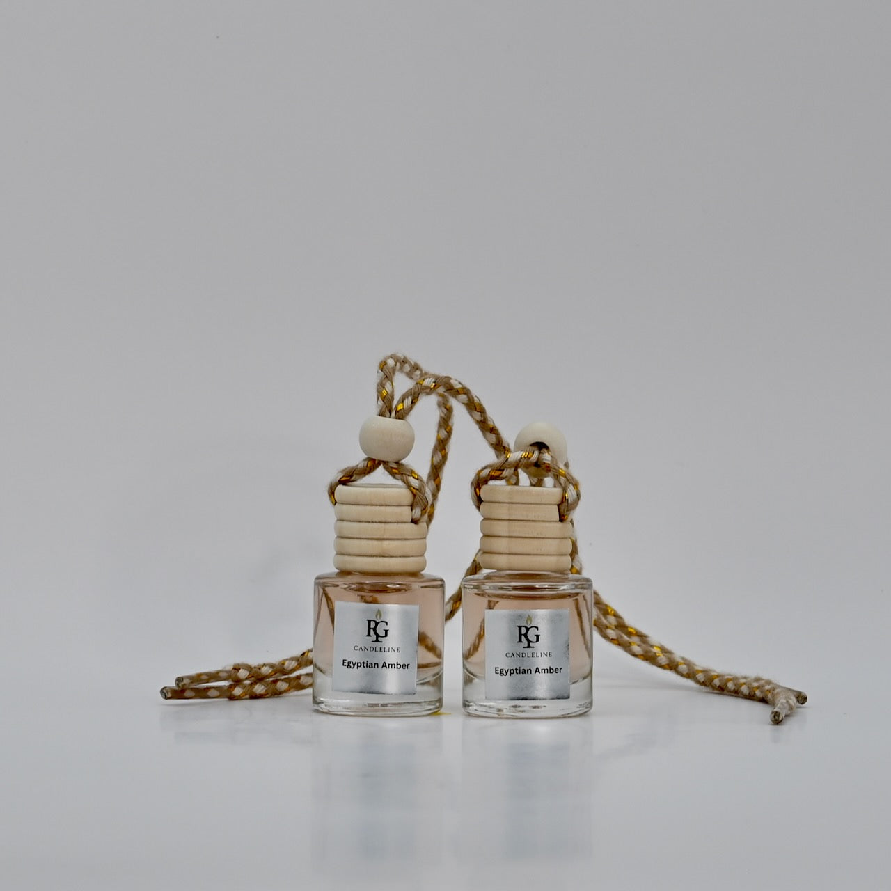 Two small perfume bottles with wooden necks and gold chains on a light gray background