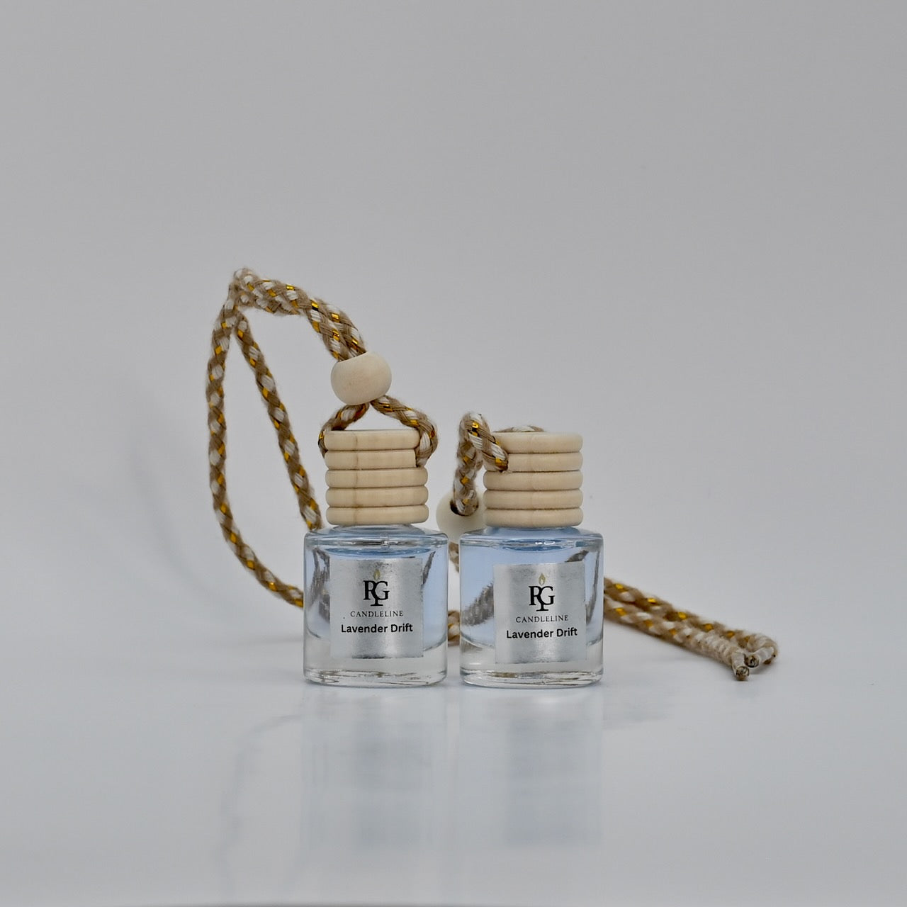 Two clear car air fresheners with wooden diffusers on a white background