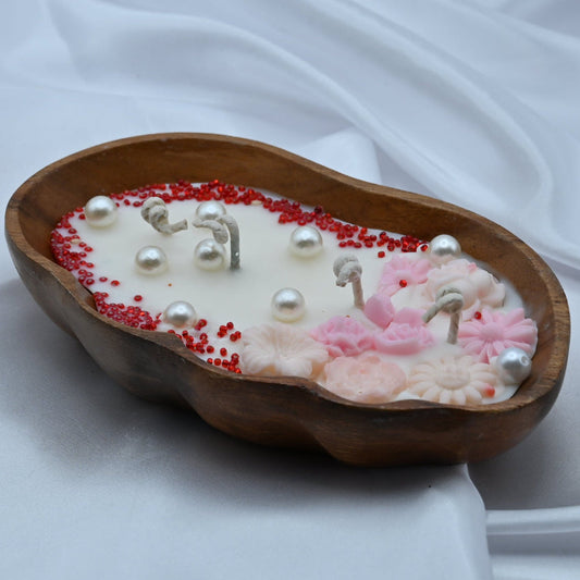 Decorative candle with pearls and red beads in a wooden bowl 