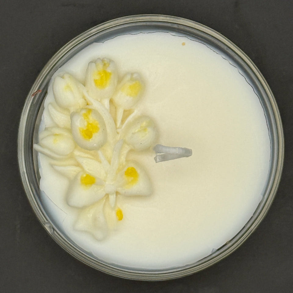 Candle with floral design in a glass container on a dark background