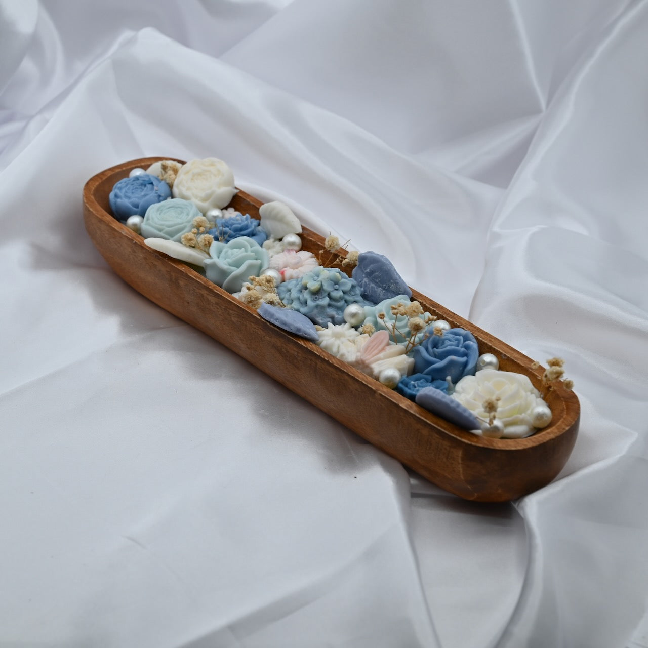 Left view of floral wooden dough bowl candle with blue and ivory wax flowers and pearl accents