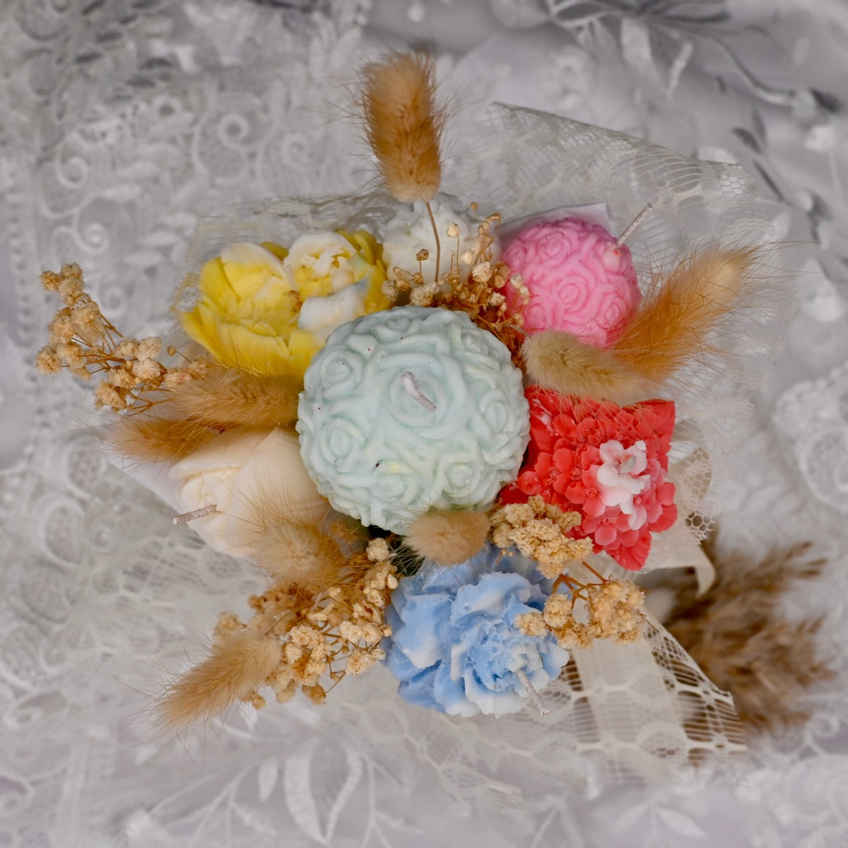 Colorful soy wax flower candle arrangement with decorative accents on a textured background