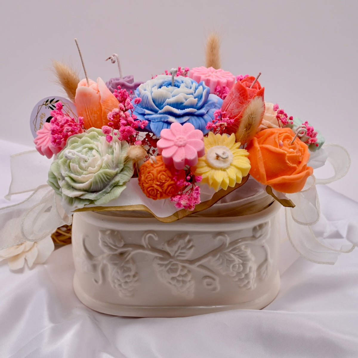 Decorative vase arrangement of colorful soy wax flower candles on a white background