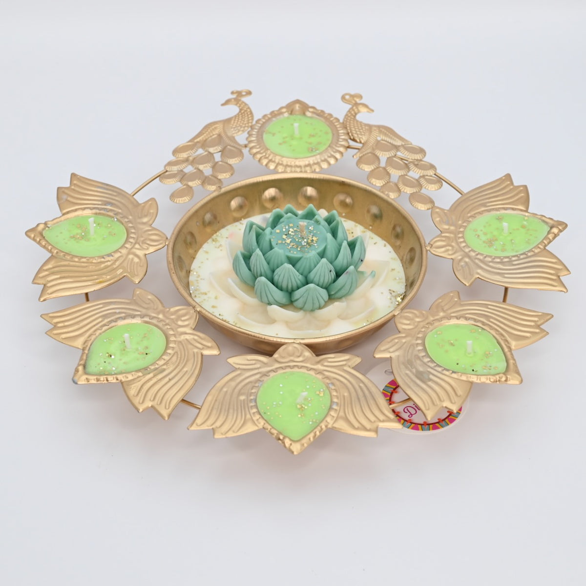 Front view of the Green Lotus Peacock Metal Urli Candle Arrangement with gold-toned peacocks, leaf-shaped candle holders, and a green floral centerpiece.