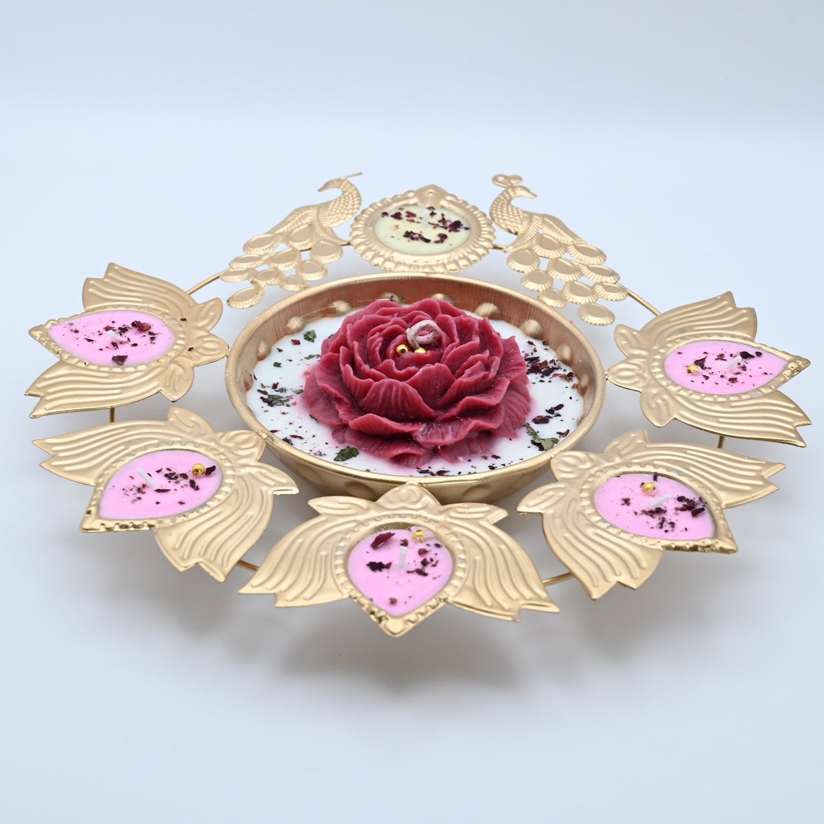 Front view of the Red Peony Peacock Metal Urli Candle Arrangement with gold-toned peacocks, leaf-shaped candle holders, and a red floral centerpiece.