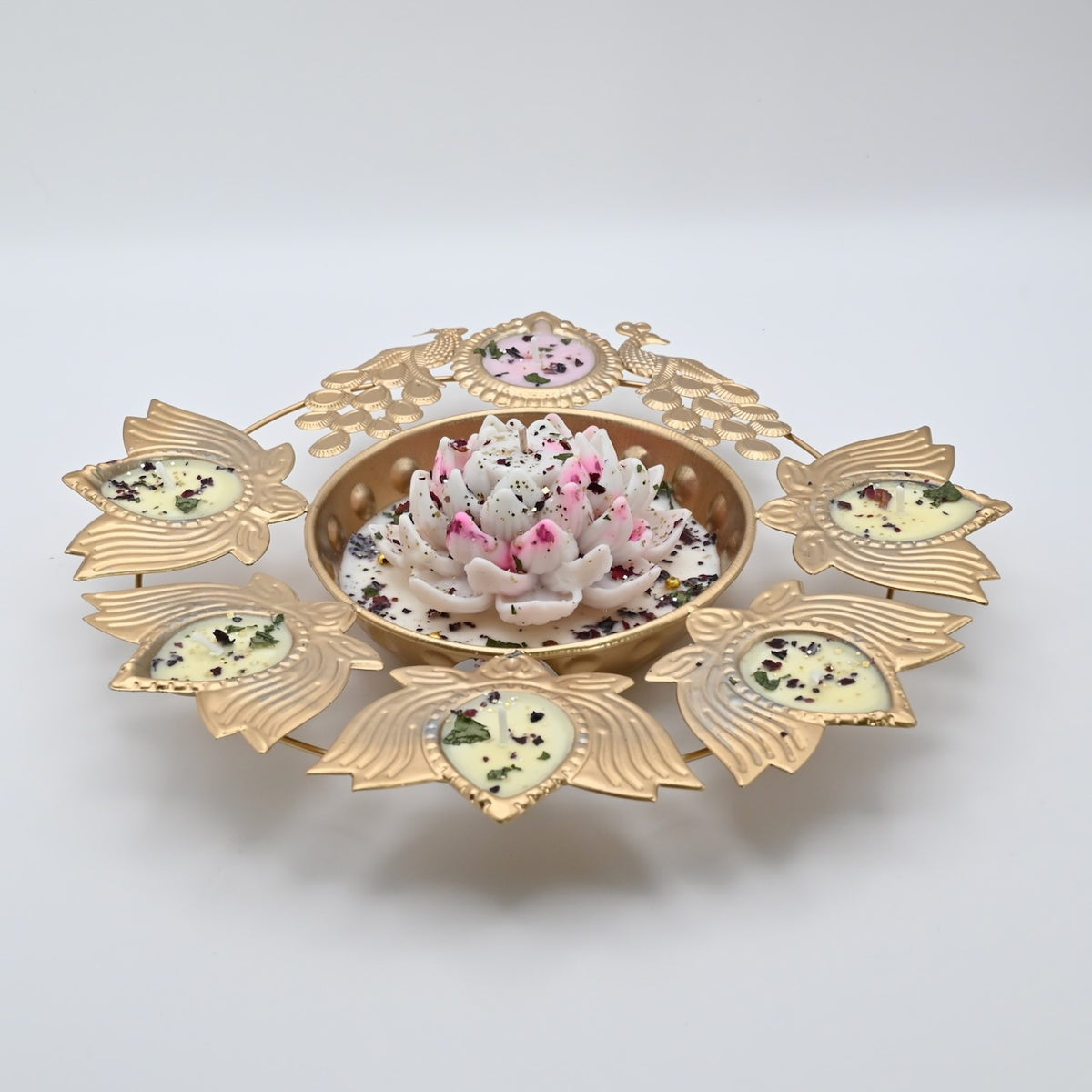 Front view of the White Lotus Peacock Metal Urli Candle Arrangement with gold-toned peacocks, leaf-shaped candle holders, and a white floral centerpiece.