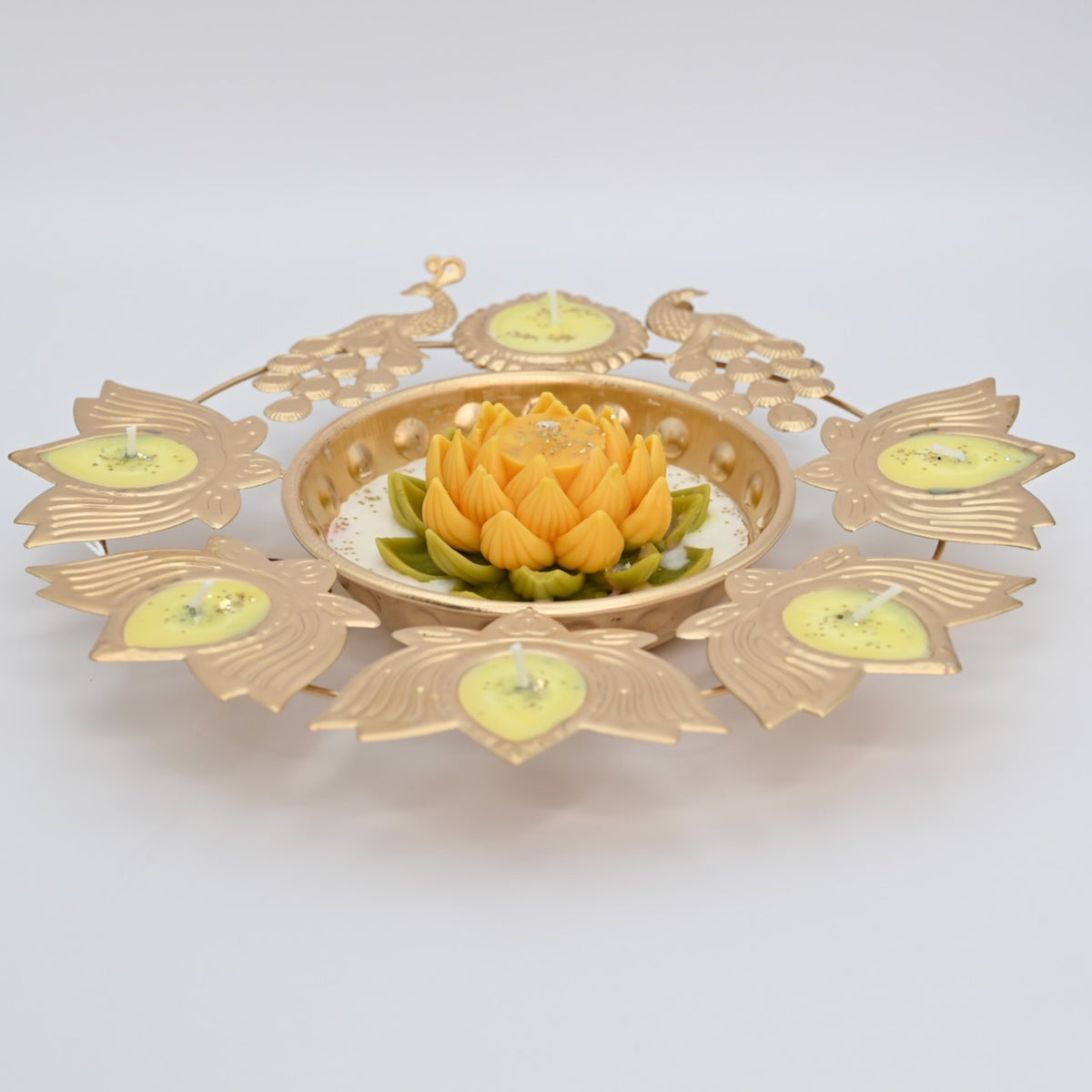 Front view of the Yellow Lotus Peacock Metal Urli Candle Arrangement with gold-toned peacocks, leaf-shaped candle holders, and a yellow floral centerpiece.