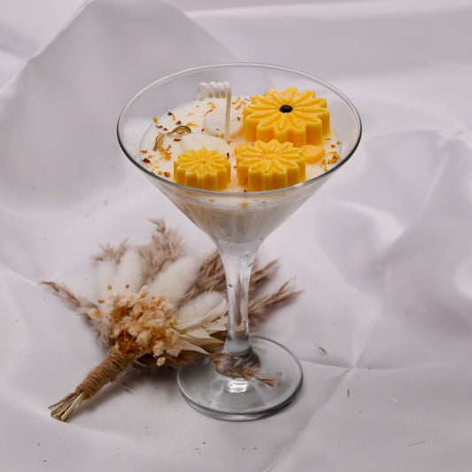 Yellow daisy-shaped soy wax flowers in a cream soy wax filled in martini glass with dried flowers.