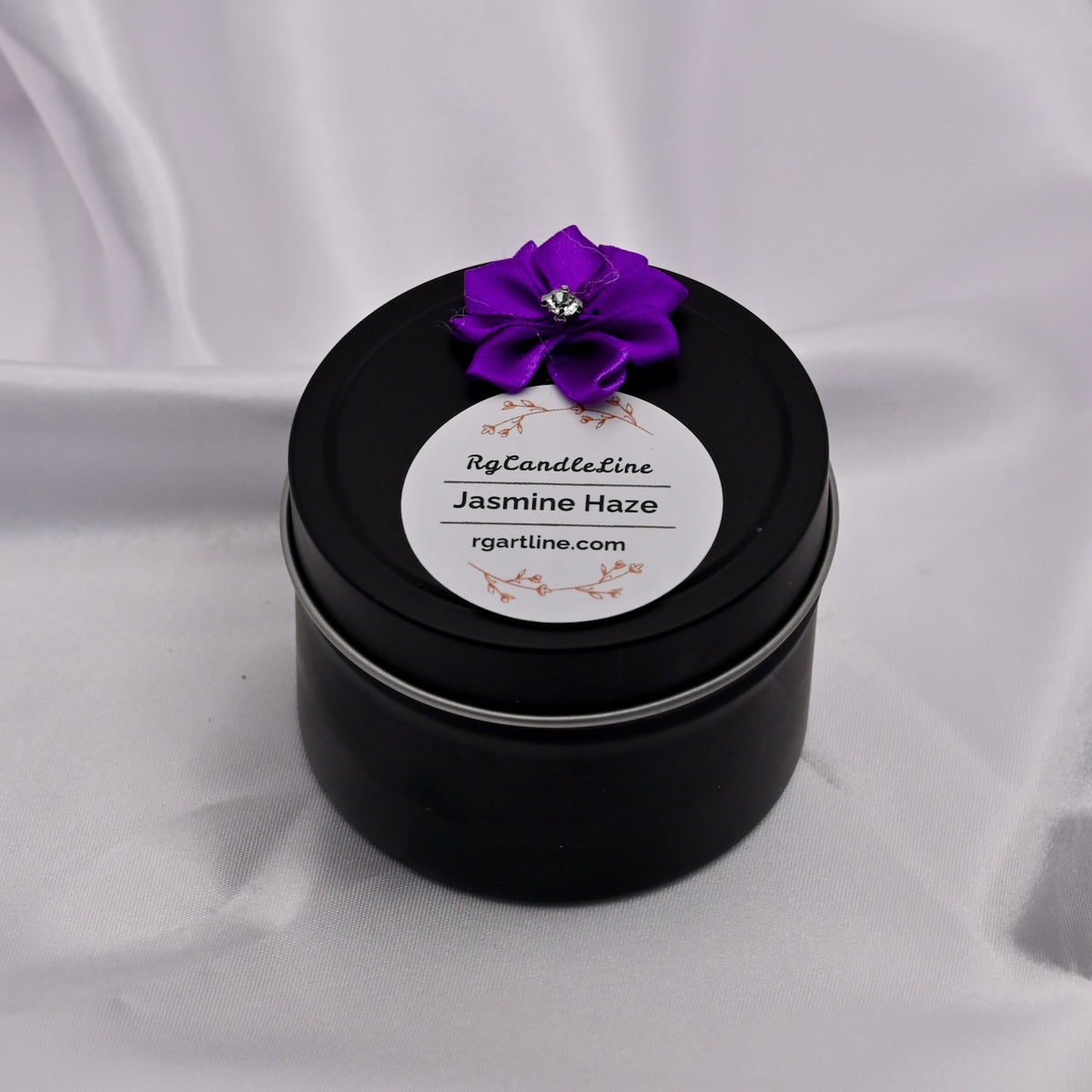 Black candle tin with a purple flower on top against a white background