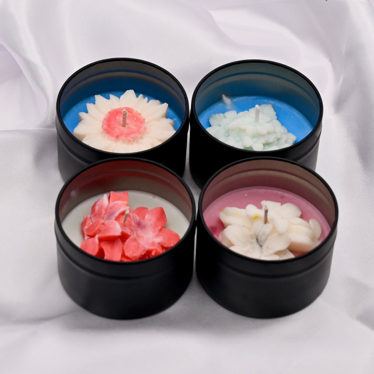 Four black containers with decorative candles inside on a white background
