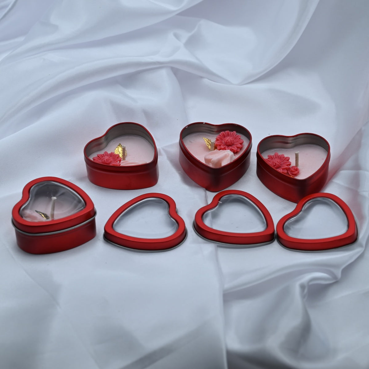 Love Spark mini Valentine candle set with three open red heart tins, one closed tin, and heart-window lids on white satin.