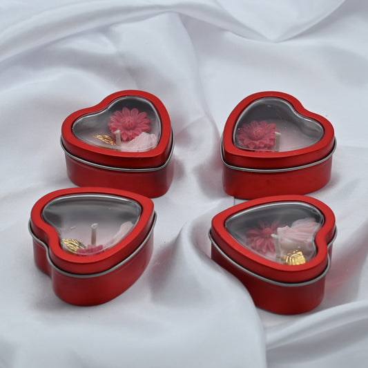 Four Love Spark mini soy wax candles in red heart-shaped tins with clear window lids, displayed on white satin.