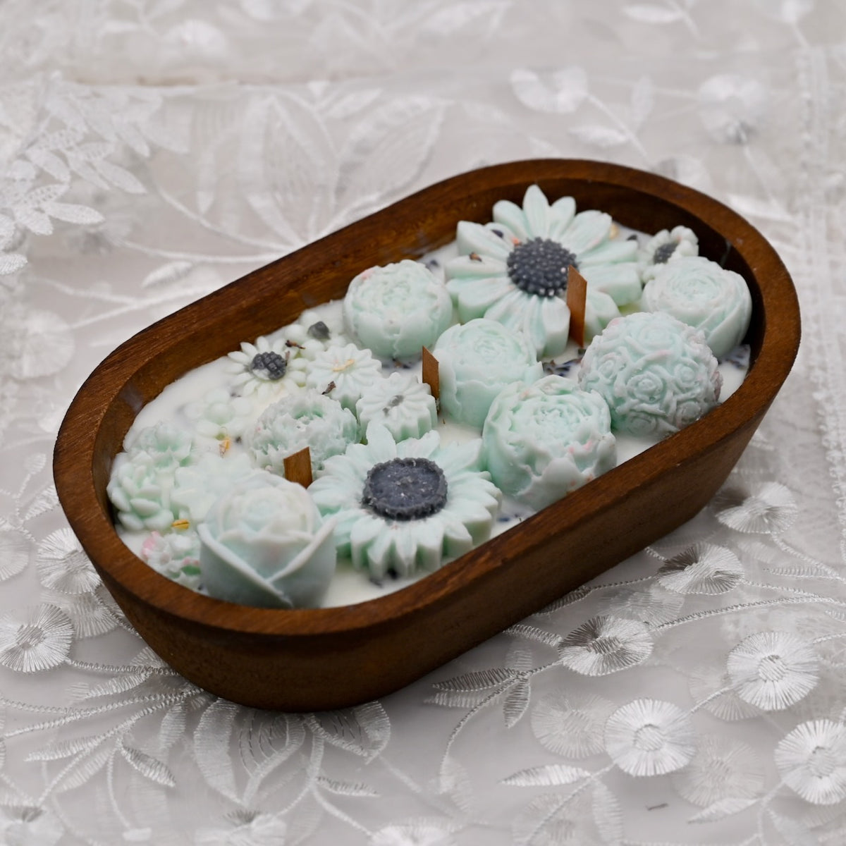 Left view of a cyan soy wax flower candle arrangement in a handcrafted wooden bowl
