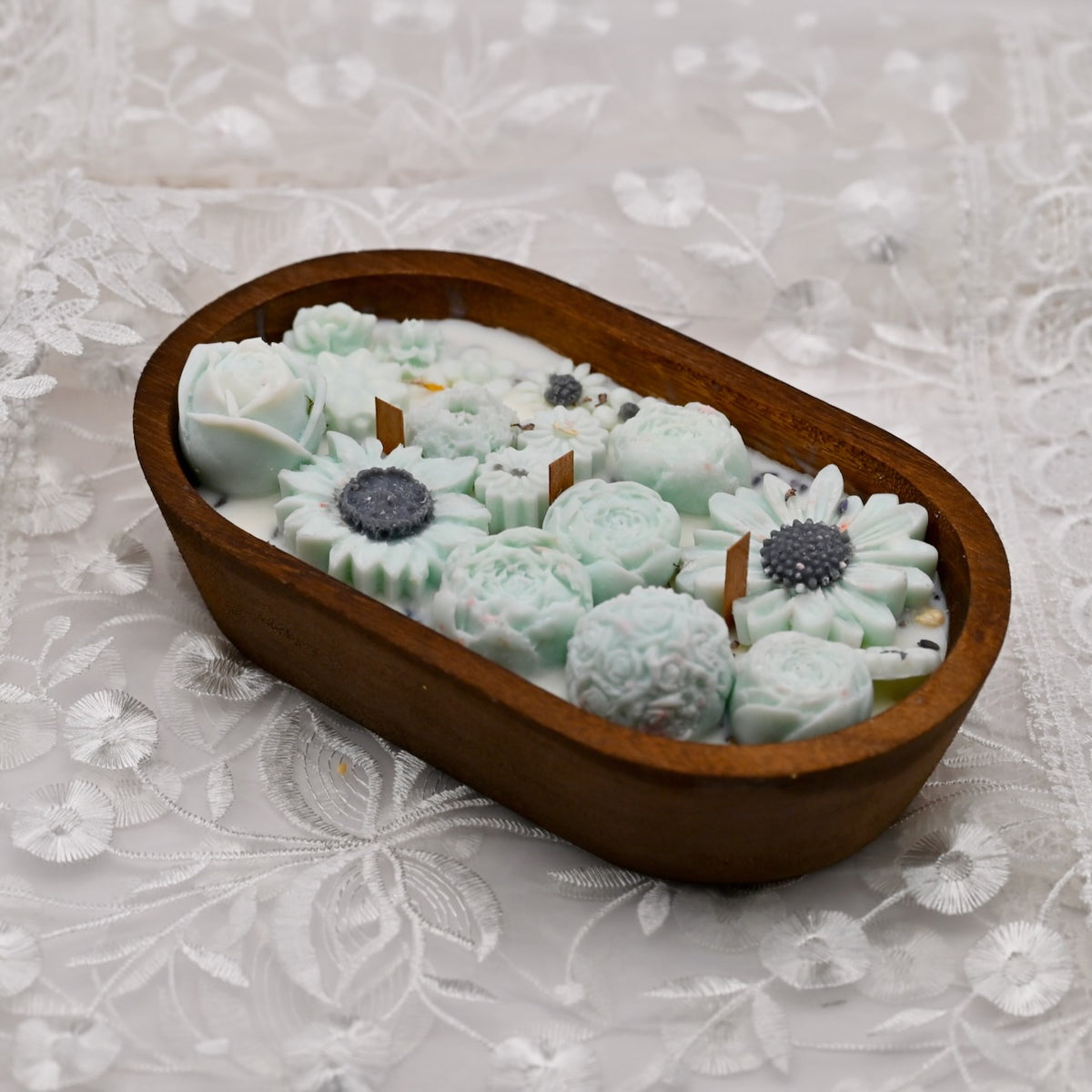 Cyan soy wax flower candle arrangement in a handcrafted wooden bowl on a white background
