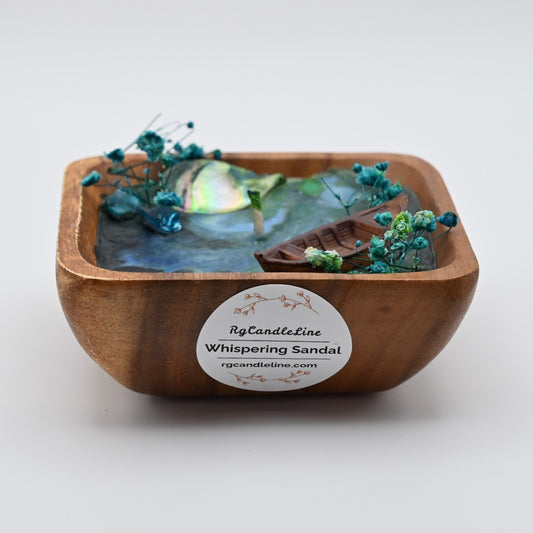 Front view of wooden bowl candle with blue wax, shell accents, dried flowers, and boat detail