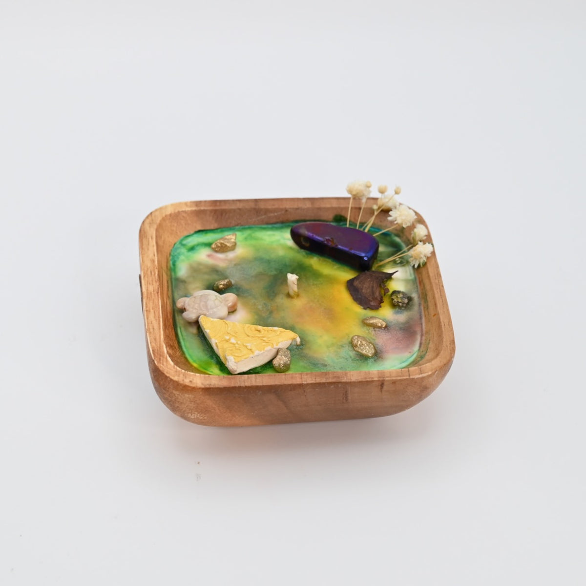 Left view of Ocean Bloom wooden bowl candle with green and yellow wax, crystal accents, and dried flowers