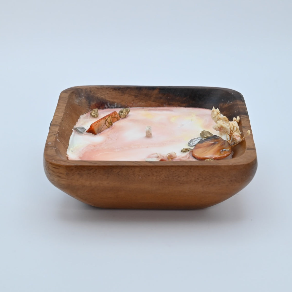 Front view of ocean Bloom wooden bowl candle with pink wax, shell, crystal, and dried flower accents