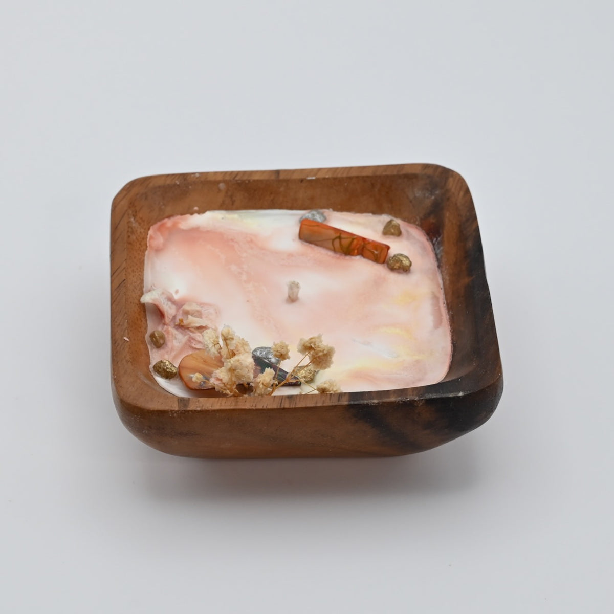 Left view of ocean Bloom wooden bowl candle with pink wax, shell, crystal, and dried flower accents