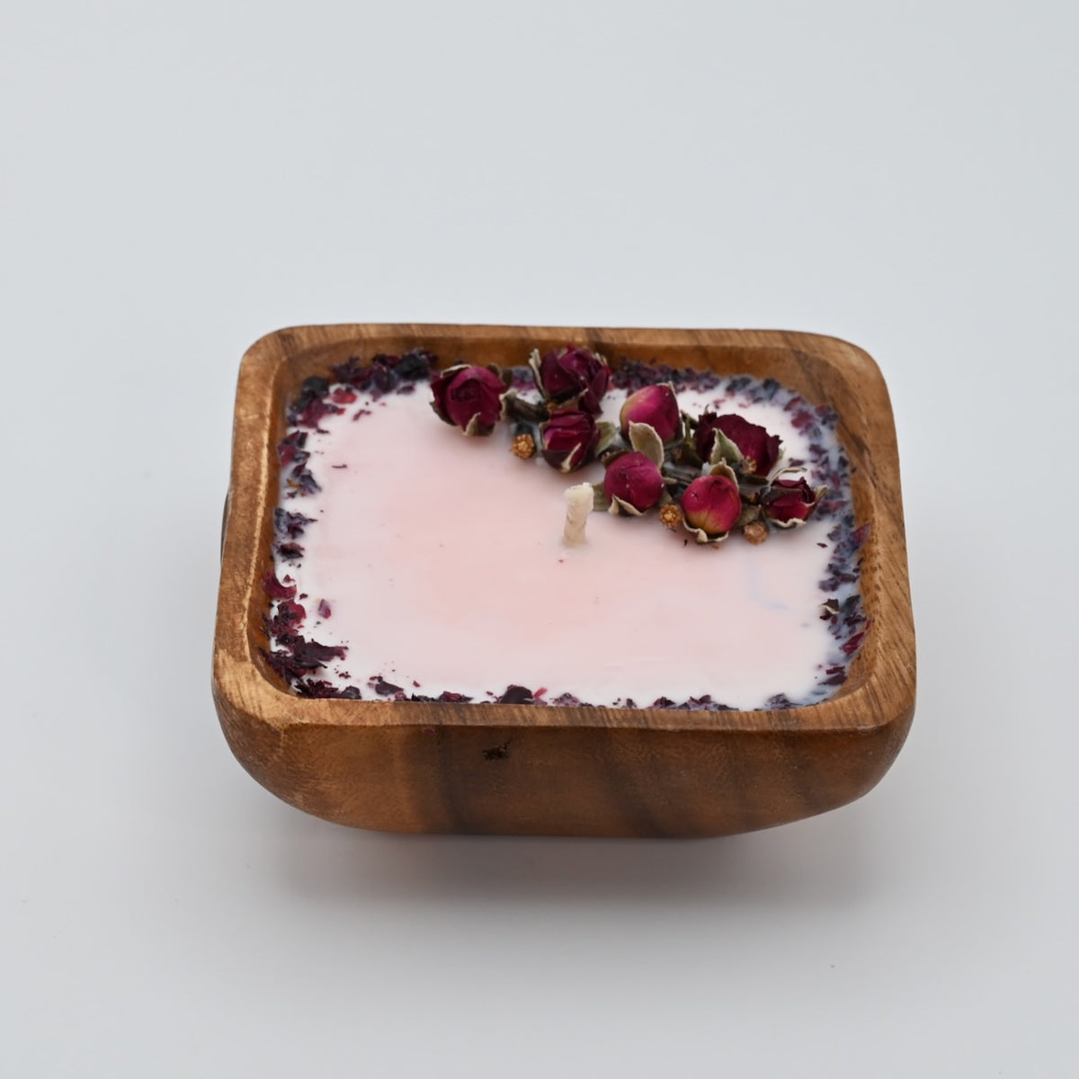 Right view of a 4-inch acacia wood bowl candle with pale wax, dried rosebuds, and a dark floral border.