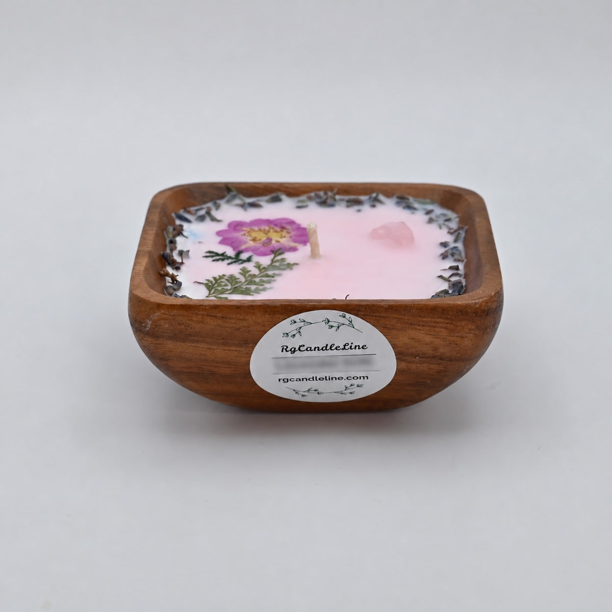 Front view of a 4-inch acacia wood bowl candle with pale wax, pressed purple flowers, and a floral border.