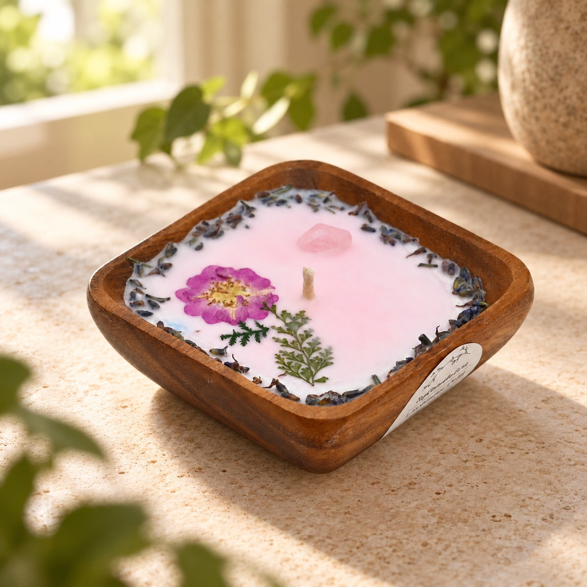 Lifestyle view of the Pressed Bloom acacia wood bowl candle styled in a softly lit home interior.