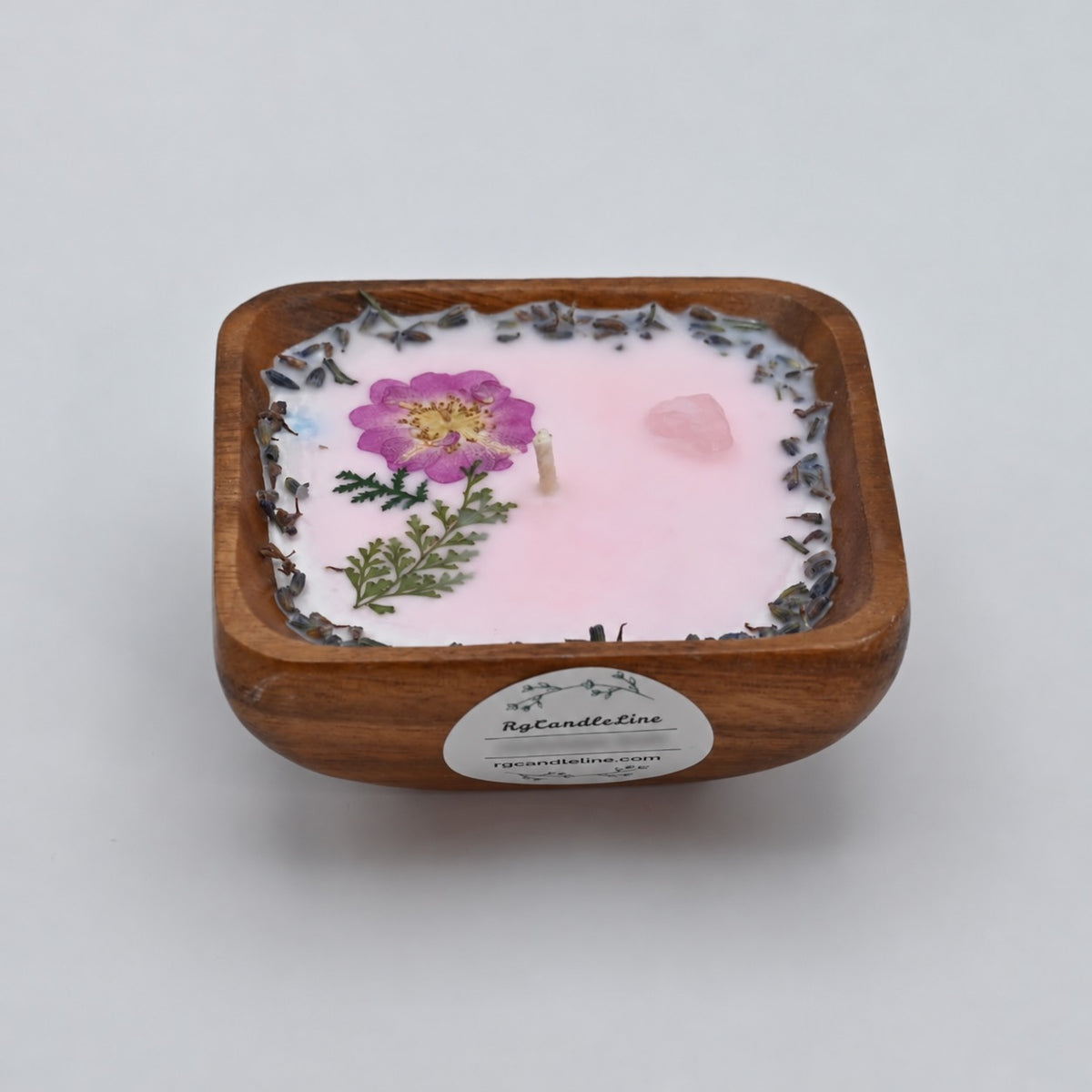 Top view of a 4-inch acacia wood bowl candle with pale wax, pressed purple flowers, and a floral border.