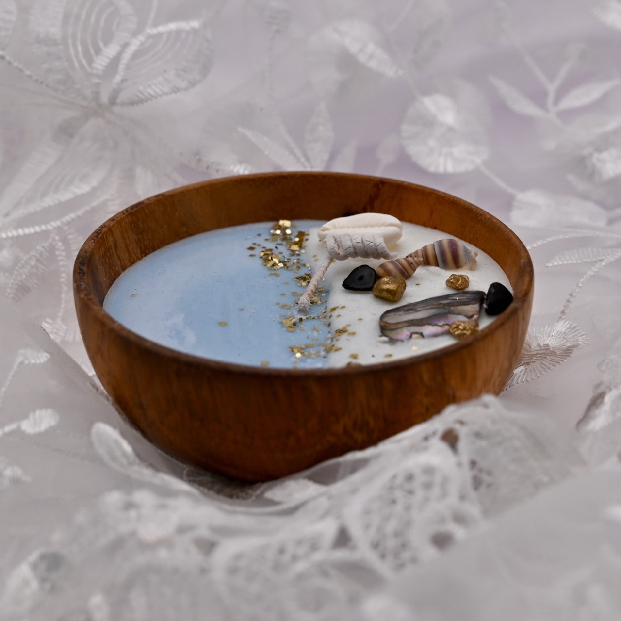 Close up view of round acacia wood bowl candle with seashell and starfish wax details