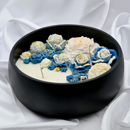 Close up of black acacia wood bowl candle with blue and white floral wax design and gold accents