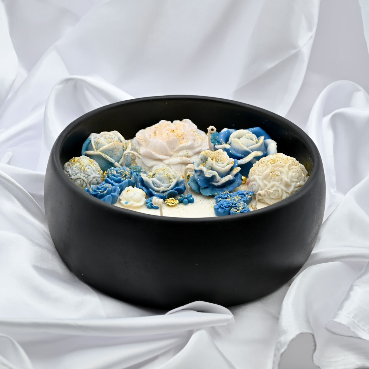 Close up top view of black acacia wood bowl candle with blue and white floral wax design and gold accents