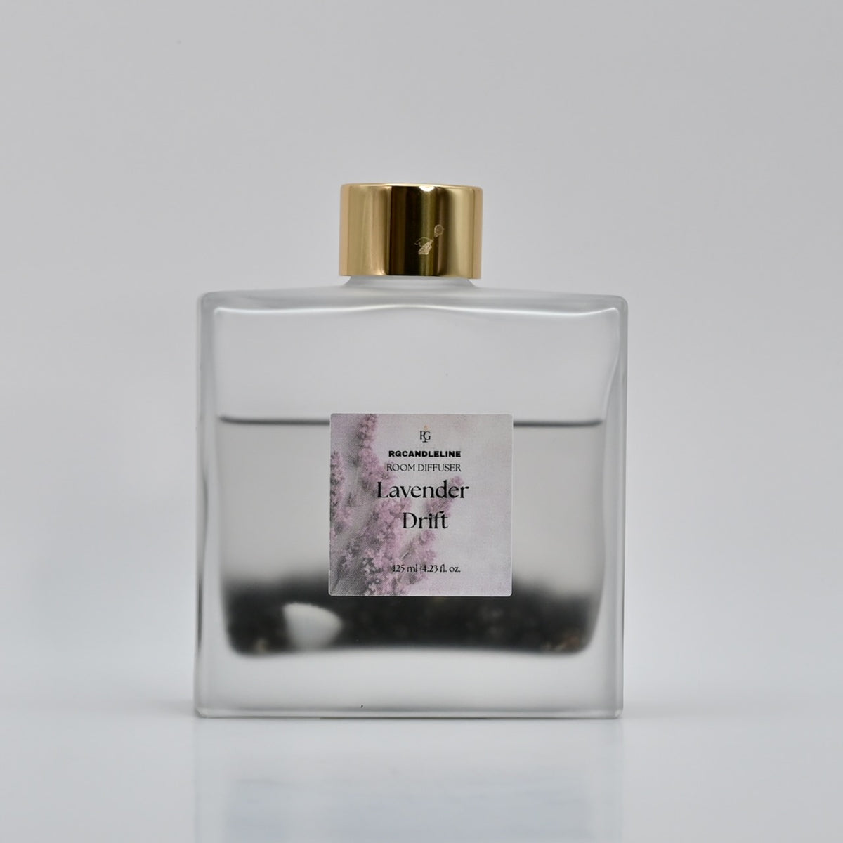 Close view of a Lavender Drift frosted square room fragrance diffuser with a gold cap and lavender-themed label.