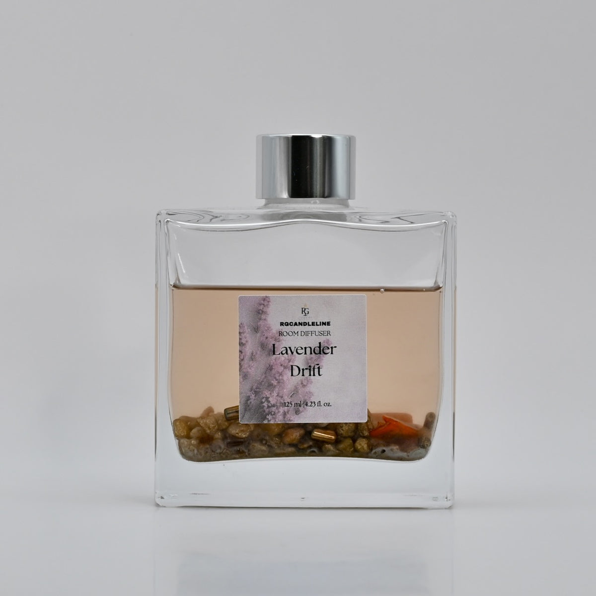 Lavender Drift frosted square room fragrance diffuser with a silver cap and decorative stones at the base.