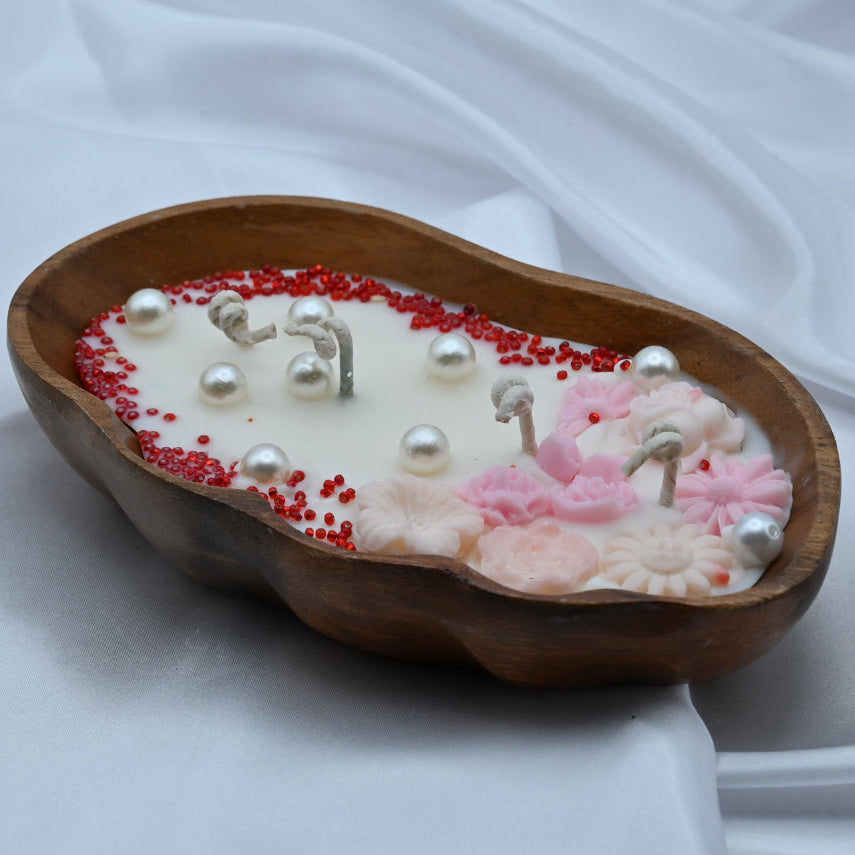 Decorative candle with pearls and red beads in a wooden bowl 