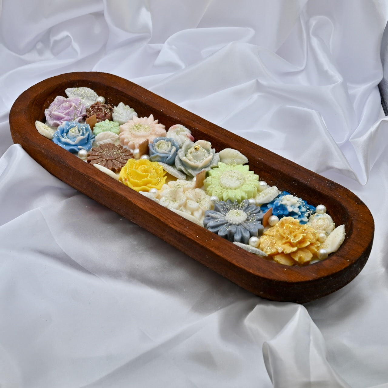 Left view of wooden tray with multiple floral-shaped colorful yellow, blue, pink candles